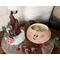 This is Crumble the Elf with his hat off, placed next to him. You can see the inside of the gourd is unfinished. Jingle bells lay nearby. 